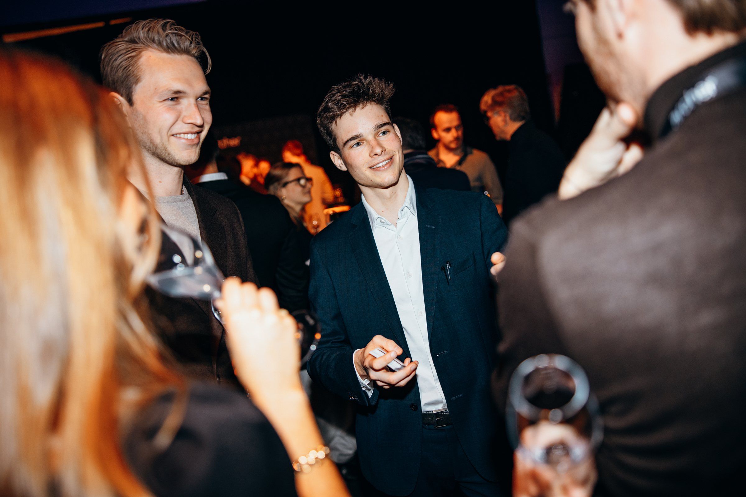 Jonas De Bruyn performing close-up card magic for guests at an evening reception