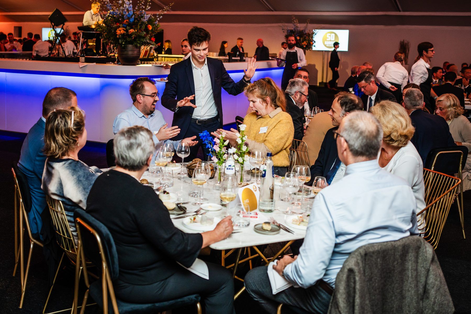 Guests at a corporate gala dinner reacting with laughter as Jonas De Bruyn performs