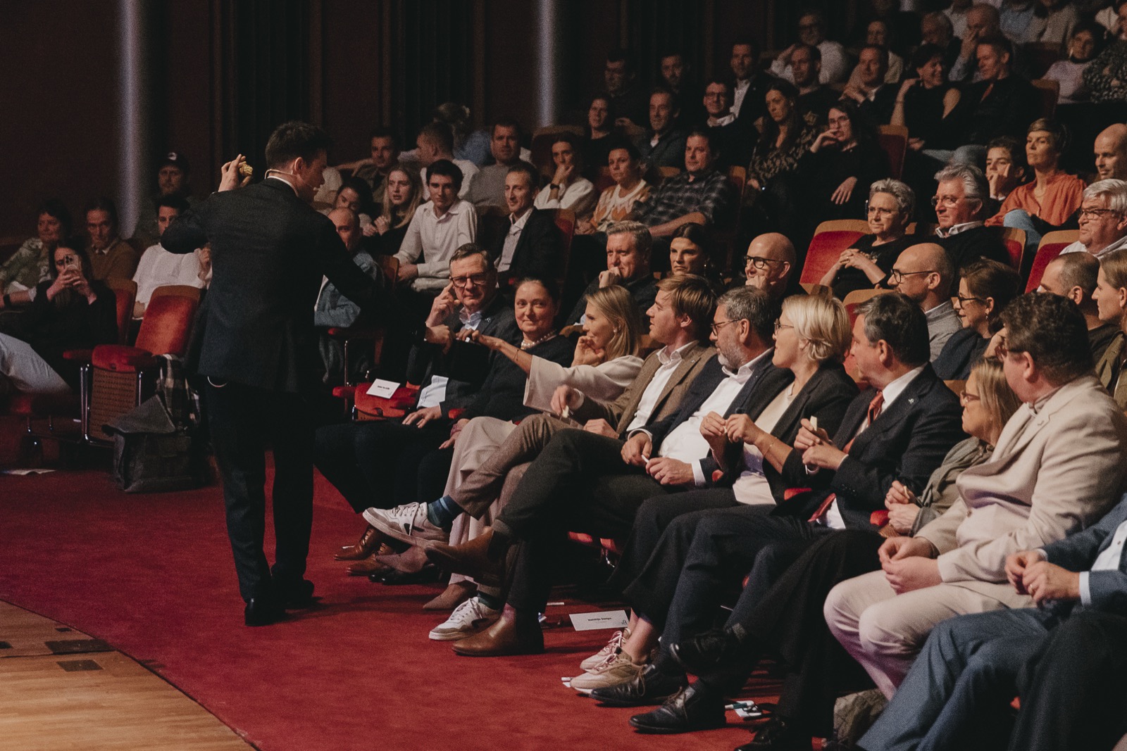 An engaged theatre audience reaching out to interact during a keynote performance